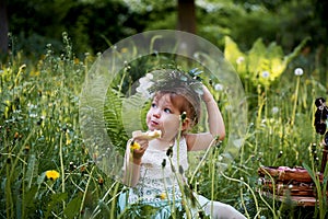 Beautiful little girl in a wreath on the head in green and white. Dress, Princess. With pleasure, but the nature