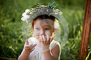 Beautiful little girl in a wreath on the head in green and white. Dress, Princess. With pleasure, but the nature