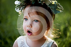 Beautiful little girl in a wreath on the head in green and white. Dress, Princess. With pleasure, but the nature