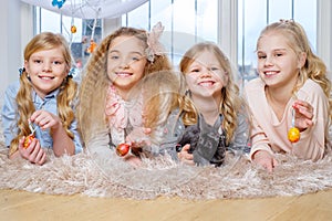 Beautiful little girls lying on carpet and playing with cute bunny.