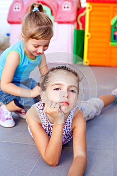 Beautiful little girls lying on playground floor