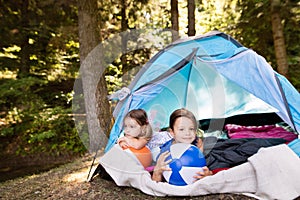 Beautiful little girls in tent camping in the forest.