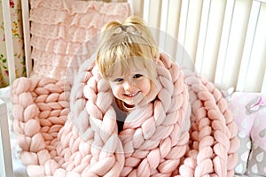 Little Girl Sitting on Bed with a Knitted Giant Plaid