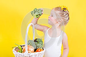Beautiful little happy girl with basket of vegetables and fruits