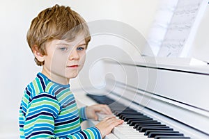 Beautiful little kid boy playing piano in living room or music school