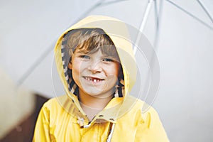 Beautiful little kid boy on way to school walking during sleet, heavy rain and snow with an umbrella on cold day. Happy