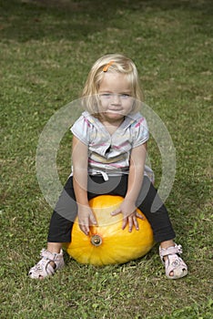 Beautiful little kid girl having fun with farming on organic pumpkin patch