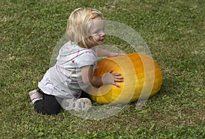 Beautiful little kid girl having fun with farming on organic pumpkin patch