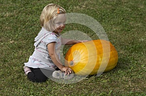 Beautiful little kid girl having fun with farming on organic pumpkin patch