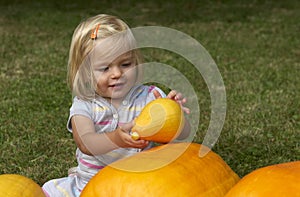 Beautiful little kid girl having fun with farming on organic pumpkin patch