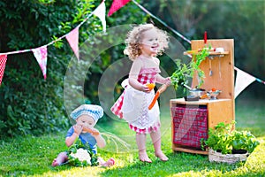 Beautiful little kids playing with toy kitchen in the garden