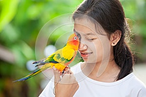 Little parrot birds standing on woman hand. Asian teenager girl play with her pet parrot bird with fun and love