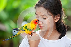 Beautiful parrot birds standing on woman hand. Asian teenager girl play with her pet parrot bird with fun and love