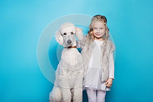 Beautiful little princess with dog. Friendship. Pets. Studio portrait over blue background