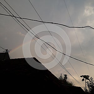 a beautiful little rainbow that quickly disappears with a roof and power lines, photo taken from the village