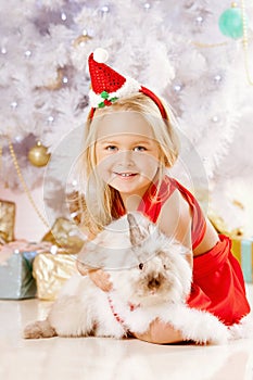 Beautiful little Santa girl near the Christmas tree. Happy girl