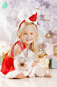 Beautiful little Santa girl near the Christmas tree. Happy girl