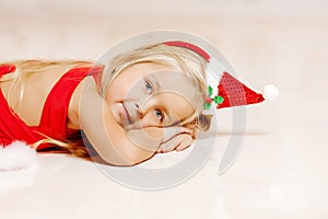 Beautiful little Santa girl near the Christmas tree. Happy girl