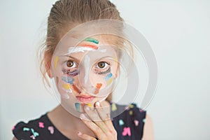 Beautiful little serious caucasian girl with face painted with colorful paint with copy space
