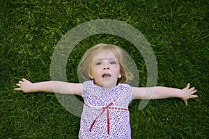 Beautiful little toddler girl happy lying on grass