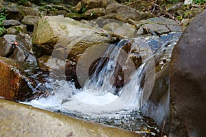 Beautiful little waterfall in mountains. Water flows between stones