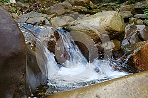 Beautiful little waterfall in mountains. Water flows between stones