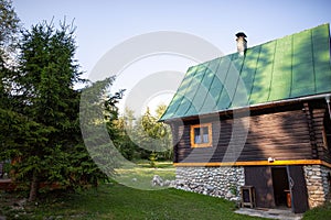 Krásná malá dřevěná chata obklopená bujnou zelení na slovenském venkově