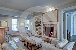 Beautiful living room in expensive home with burning fireplace and large blank picture over the mantle