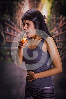 Beautiful and lonely girl suffering from anorexy, suffering pain in his stomach while she is eating an apple, in a