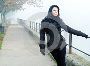 Beautiful lonely girl walking in park on misty autumn day