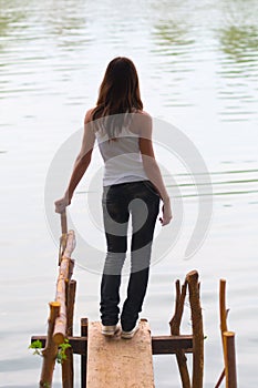 Beautiful lonely teenage girl standing on the dock