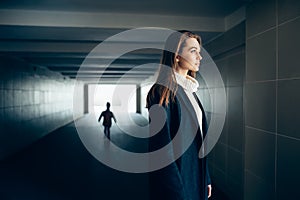 Beautiful lonely woman in subway tunnel with frighten silhouette