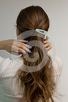 Beautiful long blond natural hair with flower hair clip snap view from the back against white background. Caucasian woman with