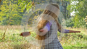 Beautiful long blonde hair girl holds yellow leaves on nature background. Smiling child plays in autumn park sunny day