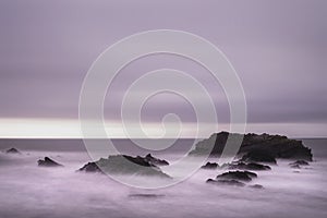 Beautiful long exposure landscape image of sea over rocks during