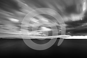 Beautiful long exposure wide angle view of a lake with an huge sky with clouds, above an island