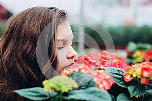 Beautiful long-haired girl in a greenhouse with spring hydrangea flowers