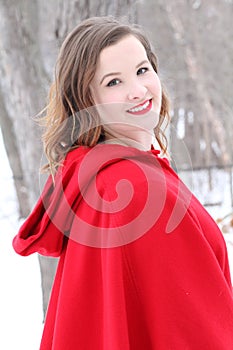 Beautiful long haired woman in red cape outdoors in winter