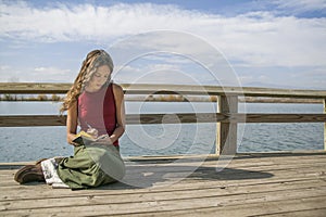 Beautiful long haired woman writing in journal near rural lake. photo