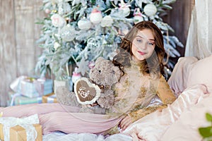 Beautiful long-haired young girl holding a Teddy bear smiles on