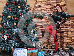 Beautiful long legged redhead girl in red stockings and heels  posing in Christmas decoration