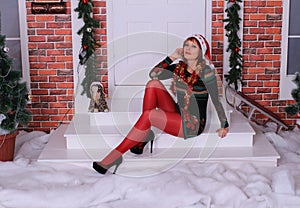 Beautiful long legged redhead girl in red stockings and heels  posing in Christmas decoration