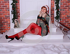 Beautiful long legged redhead girl in red stockings and heels  posing in Christmas decoration