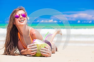 beautiful longhaired woman in sunglasses drinking coconut cocktail by the beach