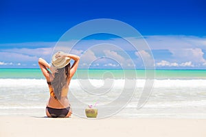 beautiful longhaired woman in sunglasses drinking coconut cocktail by the beach