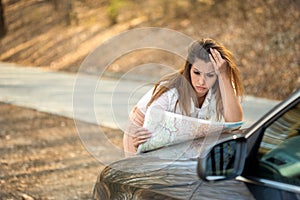 Beautiful lost woman looking at a map on the side of the road