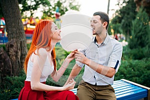 Beautiful love couple eats cotton candy on a bench