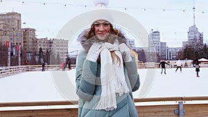 Beautiful lovely middle-aged girl with curly hair warm winter jackets stands ice rink background Town Square.