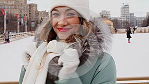 Beautiful lovely middle-aged girl with curly hair warm winter jackets stands ice rink background Town Square.