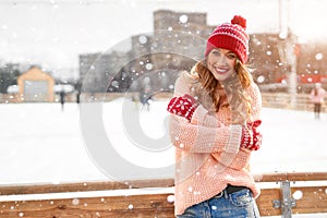 Beautiful lovely middle-aged girl with curly hair warm winter sweater stands ice rink background Town Square